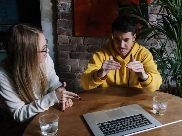 Two people with disabilities at a table speaking in sign language